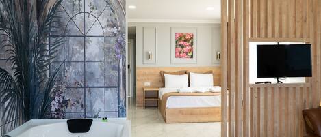A bedroom with a large bed, a TV, and a bathroom with a bathtub.