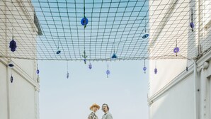A garden with red flowers and a netted structure overhead.