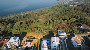 Vista aérea de una zona residencial con casas modernas, una carretera y una masa de agua al fondo.