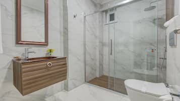 Un bagno moderno con pavimento in marmo, mobile bagno in legno, box doccia in vetro e un water.