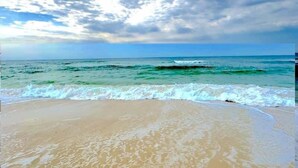 A beach with waves approaching the shore under a partly cloudy sky. - Lite House II at Martinique - Golf Cart Included - Just steps to the beach!!! (Fort Morgan)