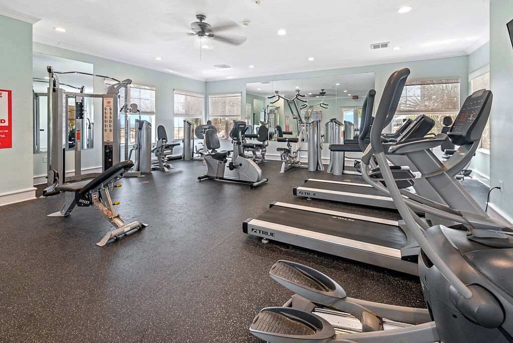 Een fitnessruimte met loopbanden, elliptische trainers en gewichten.