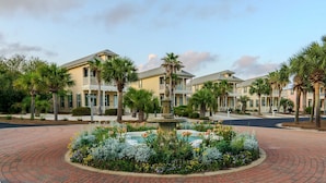 A hotel with a central courtyard featuring a fountain, surrounded by palm trees and a variety of flowers. - Lite House II at Martinique - Golf Cart Included - Just steps to the beach!!! (Fort Morgan)