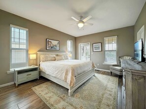 A bedroom with a bed, nightstands, a ceiling fan, and a TV. - Lite House II (Fort Morgan)