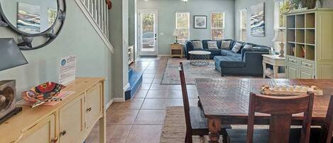 A spacious living area with a wooden dining table, a sofa, and a bookshelf.