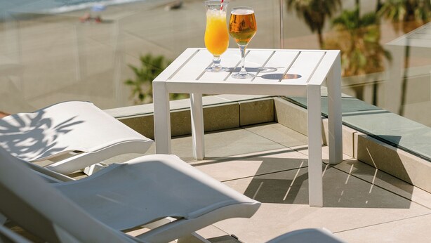 A balcony with a table and chairs overlooking a beach. - Hotel Estepona Plaza (Estepona)