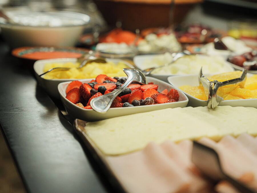 Un bufé con diversos alimentos, incluyendo frutas y un plato de carne.