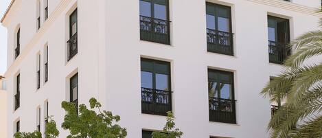 A multi-story building with balconies, surrounded by lush greenery.