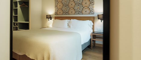 A neatly made bed with white linens, a wooden headboard, and two bedside lamps.