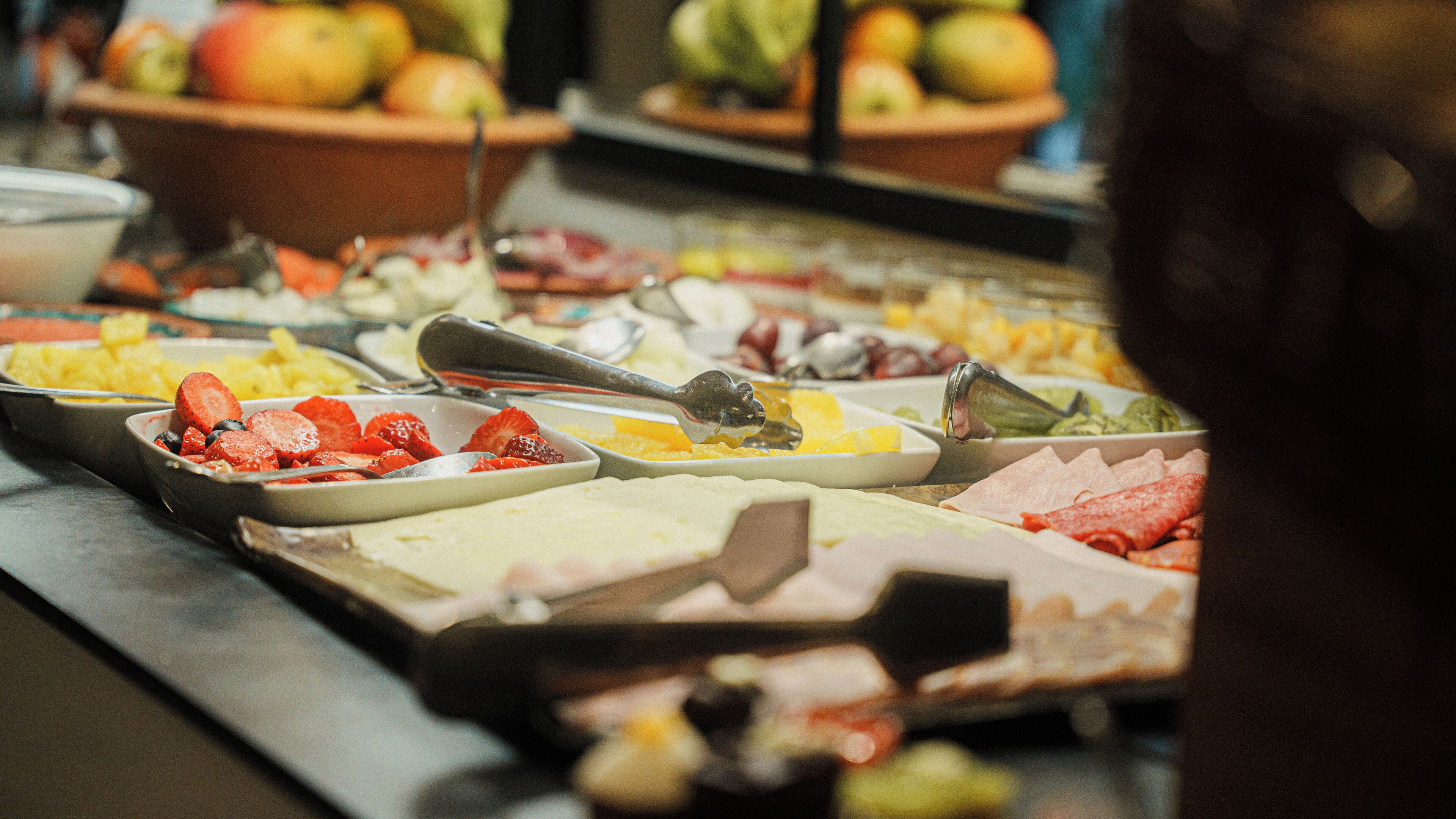 A buffet with various food items including fruits, meats, and cheeses.