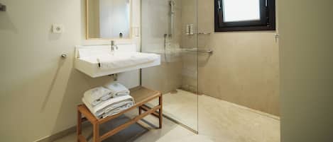 Un baño moderno con lavamanos, espejo y cabina de ducha de vidrio.
