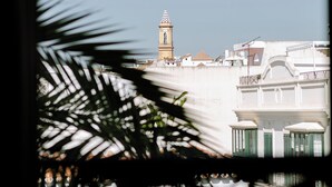 A view of a building with a clock tower, surrounded by white structures and balconies. - Hotel Estepona Plaza (Estepona)