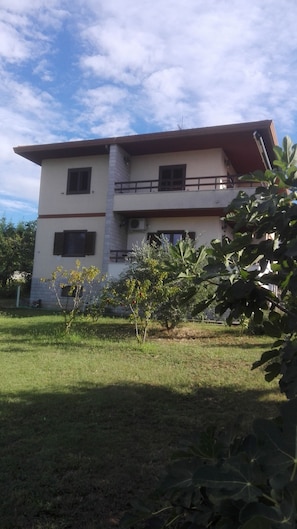 A two-story building with a flat roof, a balcony on the upper floor, and a small garden area in front. - Appartamento Nerio -avander House (Muggia)
