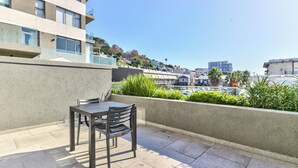 A balcony with a table and chairs, a view of the city, and a building with a balcony. - Great Studio With Balcony and City Views (Cape Town)