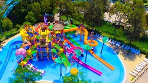 Parque acuático con una estructura central de juegos, varias toboganes y una piscina.