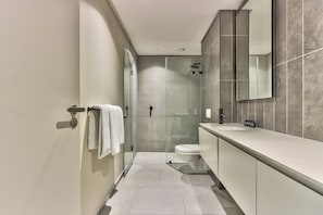 A modern bathroom with a glass-enclosed shower, a toilet, and a vanity with a mirror.