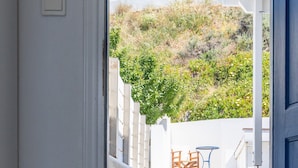 A doorway leading to a staircase with a view of a white building and greenery in the background. - Beach House With Seaview (Naxos)