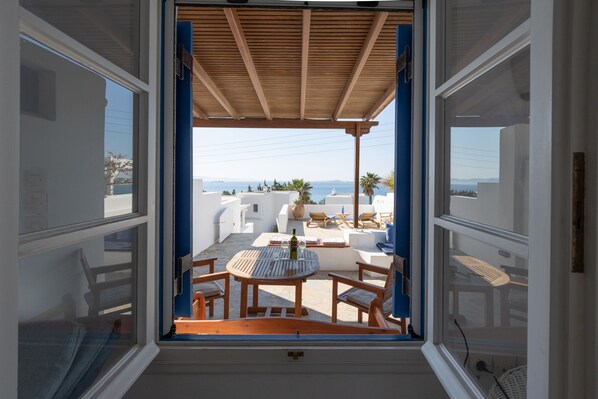 Une pièce avec une table et des chaises en bois, une vue sur la mer et une décoration aux couleurs bleu et blanc.
