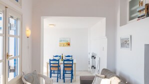 A living room with a sofa, a dining table with chairs, and a hanging light fixture. - Beach House With Seaview (Naxos)