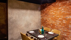 A dining area with a brick wall, a table set with plates, cutlery, and a bottle. - Treebo Fourth Avenue (Chennai)