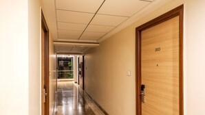 A hallway with a wooden door labeled "303" and a glass door leading to another room. - Treebo Fourth Avenue (Chennai)