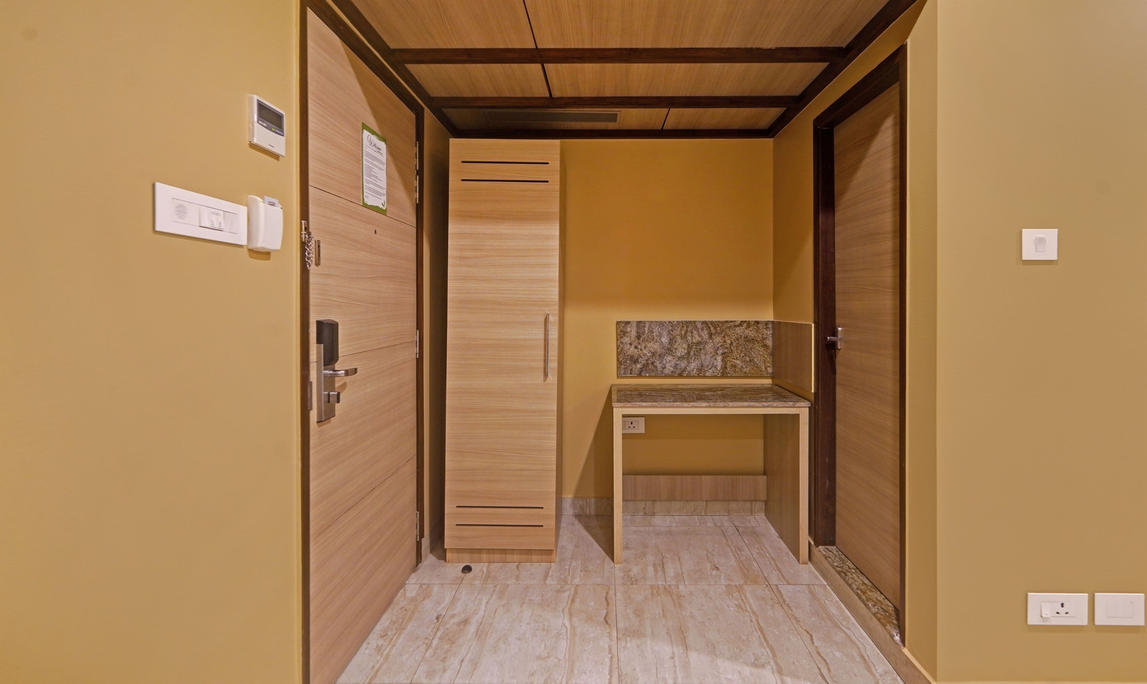 Un estrecho pasillo con puertas de madera, un banco y una pequeña mesa con encimera de mármol.