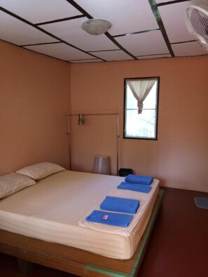 A single bed with blue towels, a ceiling fan, a window with curtains, and a small trash bin. - X-BAR and Bungalow (Trat)