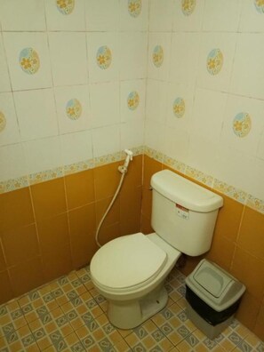 A small bathroom with a toilet, a bidet, and patterned tiles on the walls and floor. - X-BAR and Bungalow (Trat)