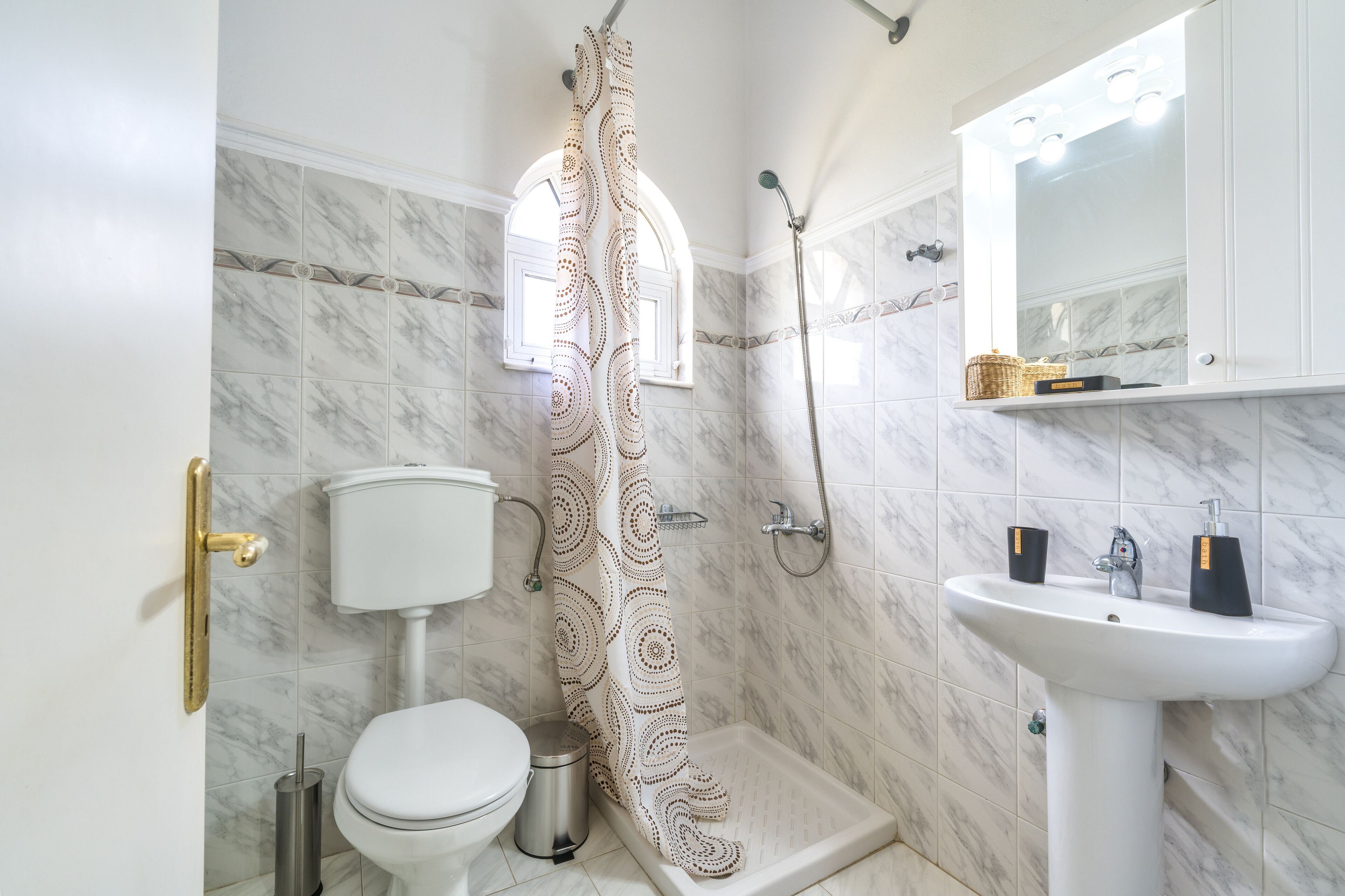 A bathroom with a toilet, shower, and sink.