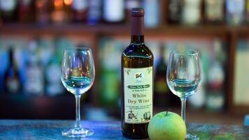 Una botella de vino blanco seco y dos copas vacías sobre una barra, con un fondo borroso de estanterías.