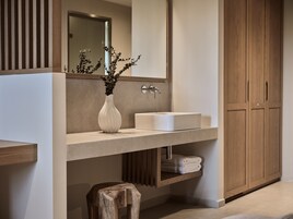 Un bagno moderno con lavandino bianco, mobile contenitore in legno e uno specchio sopra.