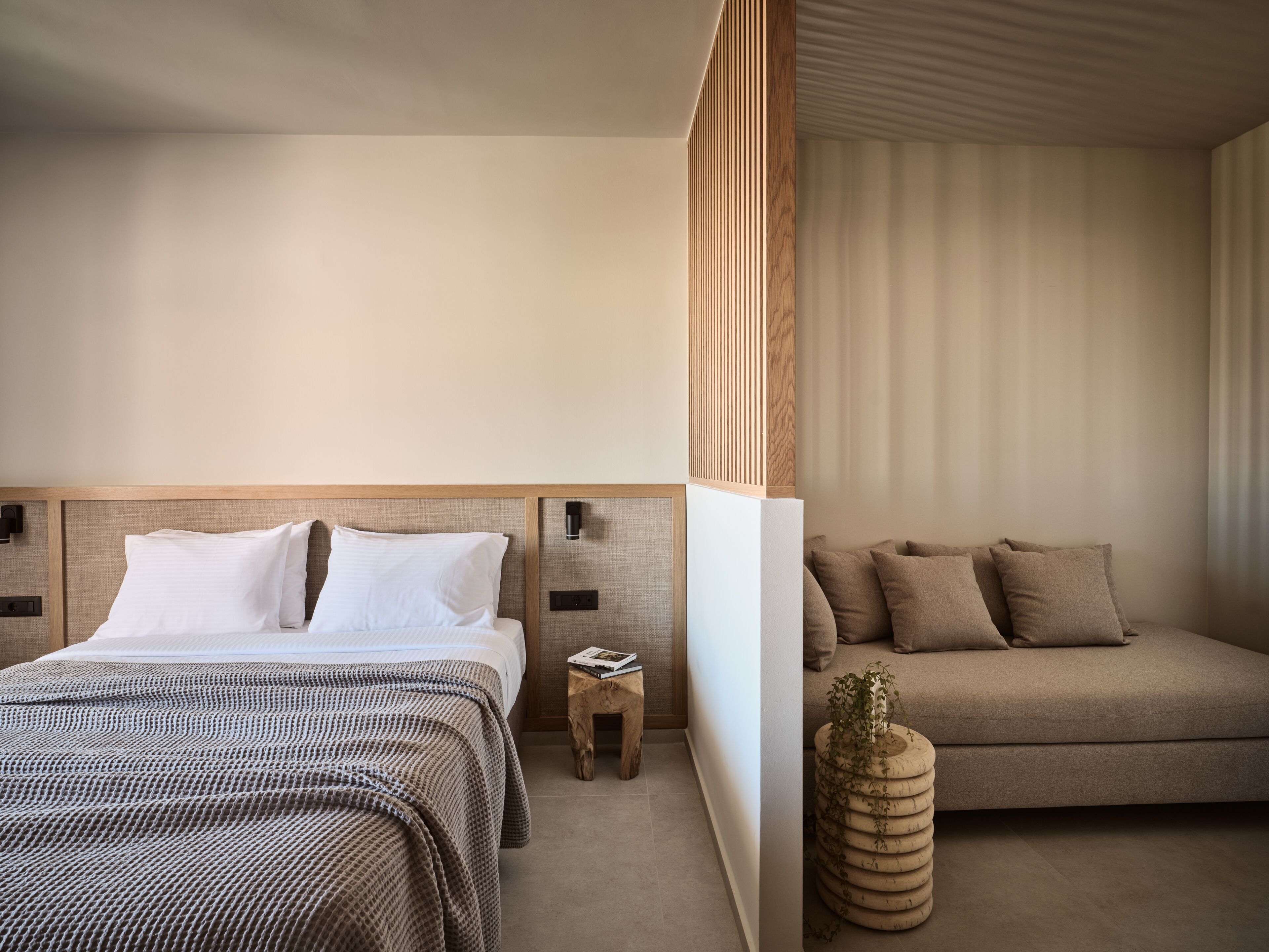 Una habitación de hotel moderna con una cama grande, un sofá y una mesita auxiliar.