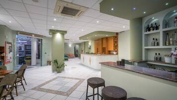 A spacious lobby with a central island, seating area, and a bar with shelves of bottles.