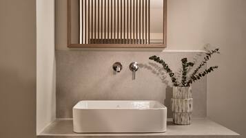 Un baño con un lavamanos rectangular, un espejo y una estantería de madera con toallas.