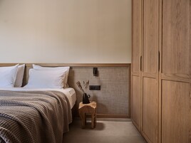 Un dormitorio con cama, mesita de noche, armario de madera y lámpara de pared.