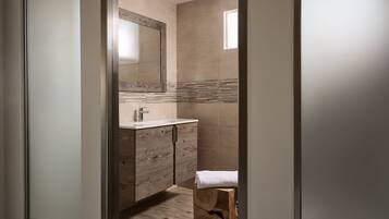 Une salle de bain moderne avec un meuble-lavabo en bois, un grand miroir et une petite fenêtre.