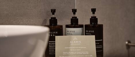 A bathroom with three bottles of Olive Era hair conditioner and a sign about sustainability practices.