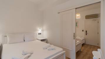 A bedroom with a bed, bedside tables, a wardrobe, and a bathroom visible through an open door.