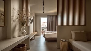 A modern hotel room with a bed, a sofa, a desk, and a window with curtains. - Alamis Hotel & Apartments (Zakynthos)