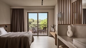 A hotel room with a bed, a desk, a chair, a vase, and a view of greenery through the balcony doors. - Alamis Hotel & Apartments (Zakynthos)
