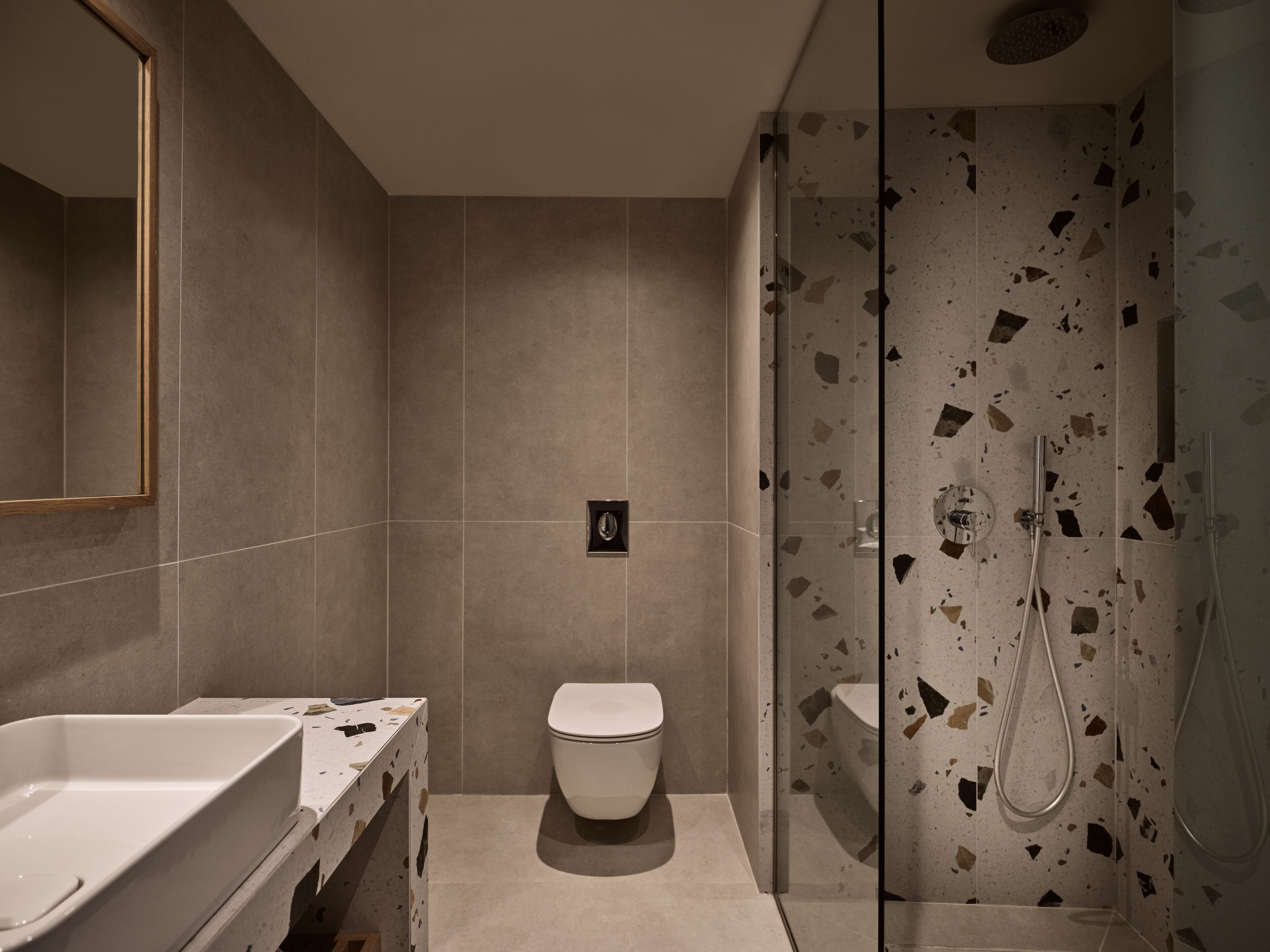 A modern bathroom with a shower, toilet, and a sink.