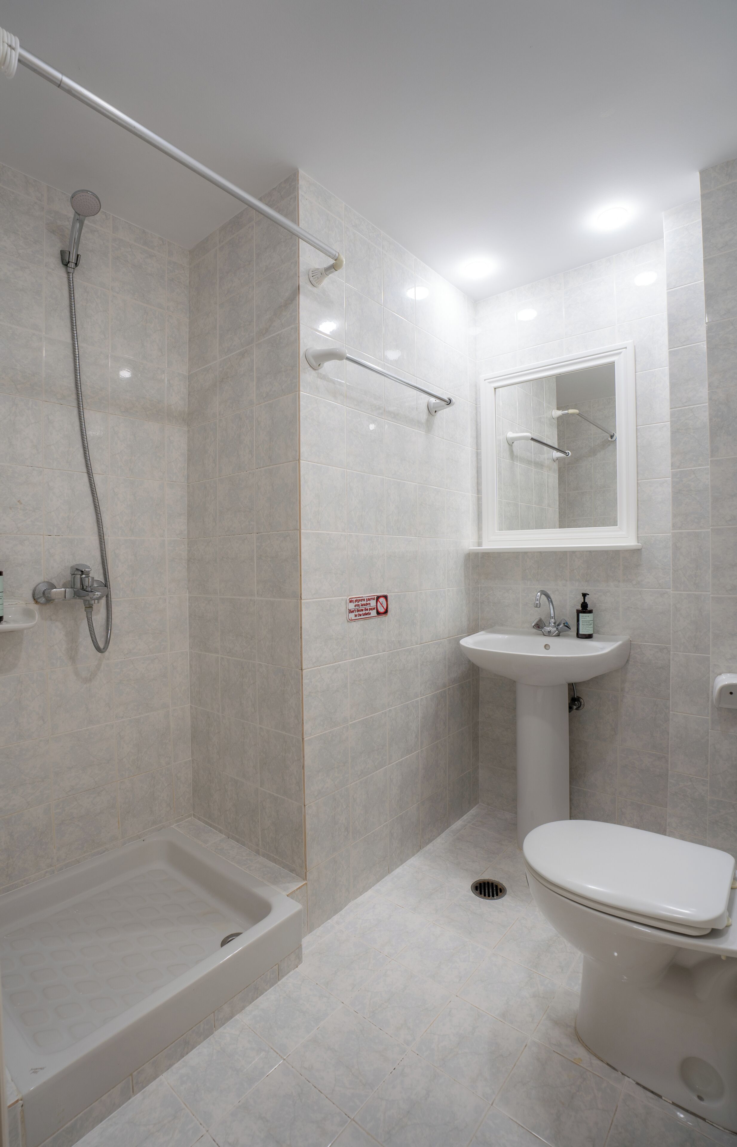 Een moderne badkamer met een inloopdouche, een wastafel op voet en een toilet.