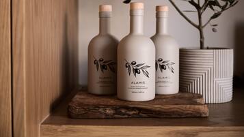 Three bottles of Alamis extra virgin olive oil on a wooden shelf.