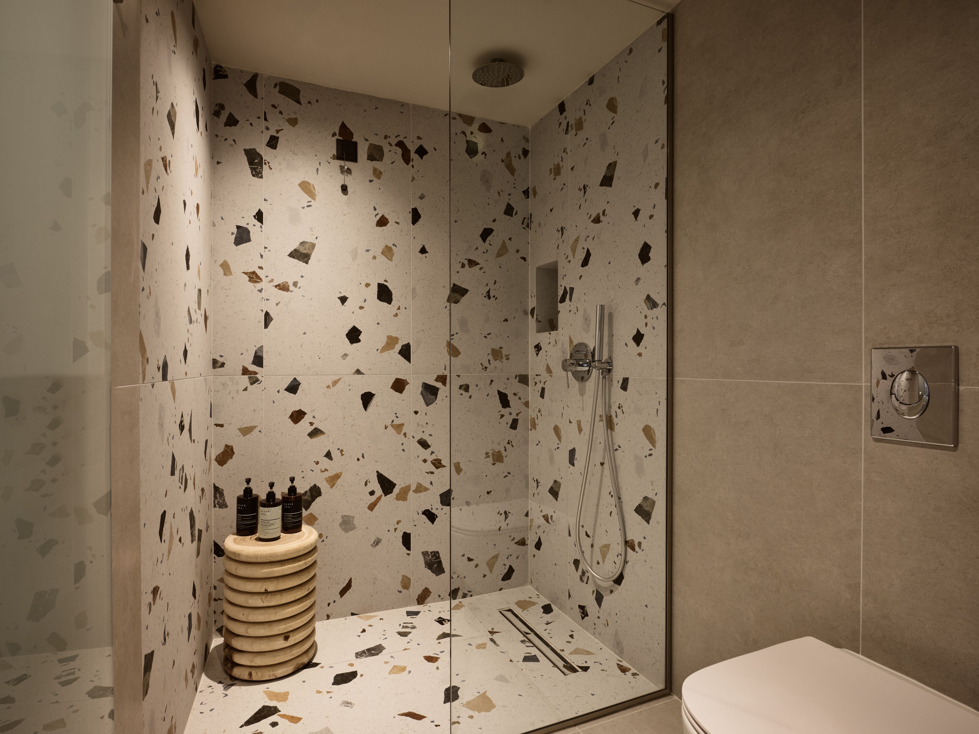 A modern bathroom with a shower, a toilet, and a sink with toiletries.