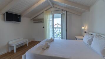 Ein Schlafzimmer mit Bett, einer Bank, einem Fernseher und Balkonblick.