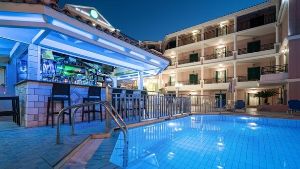 A swimming pool area with a bar and seating, surrounded by a multi-story building with balconies. - Alamis Hotel & Apartments (Zakynthos)
