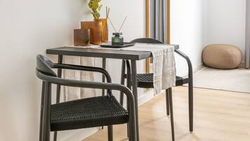 A modern dining area with a table, chairs, a plant, and a TV mounted on the wall.