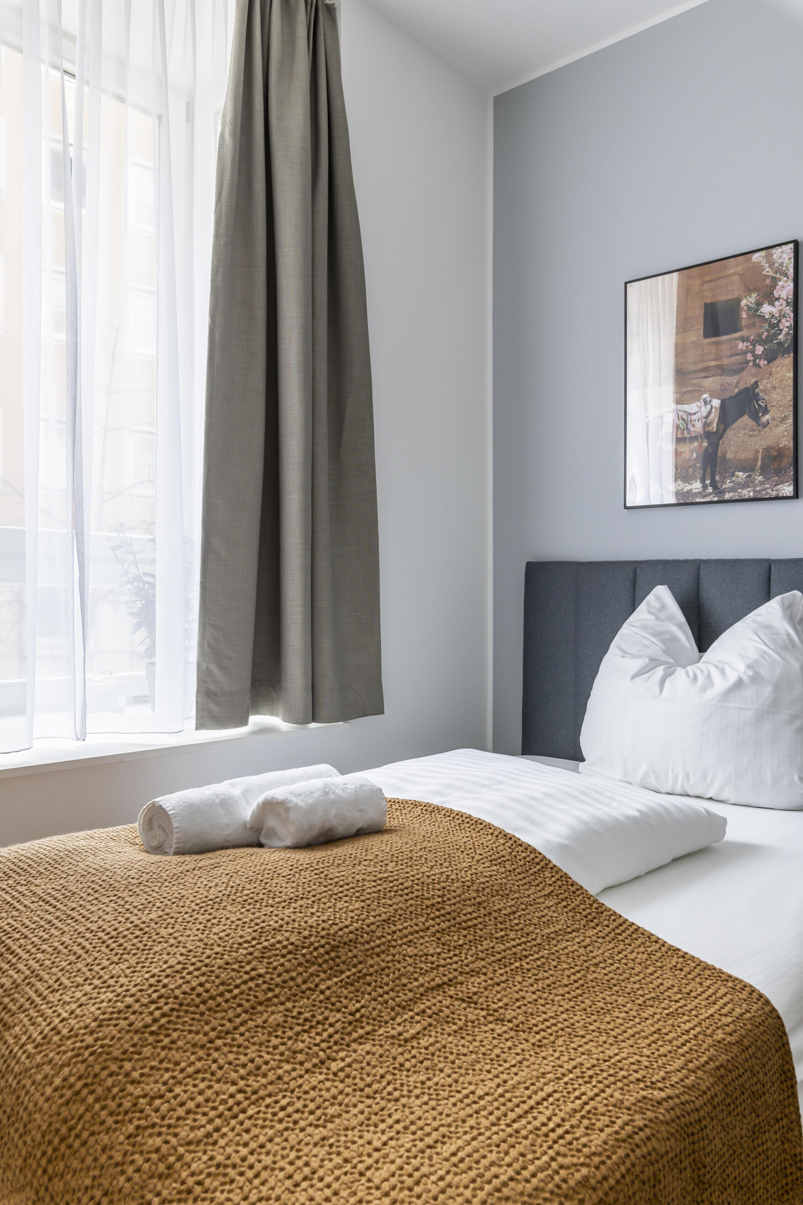 A neatly made bed with a textured brown blanket, white pillows, and a grey headboard.
