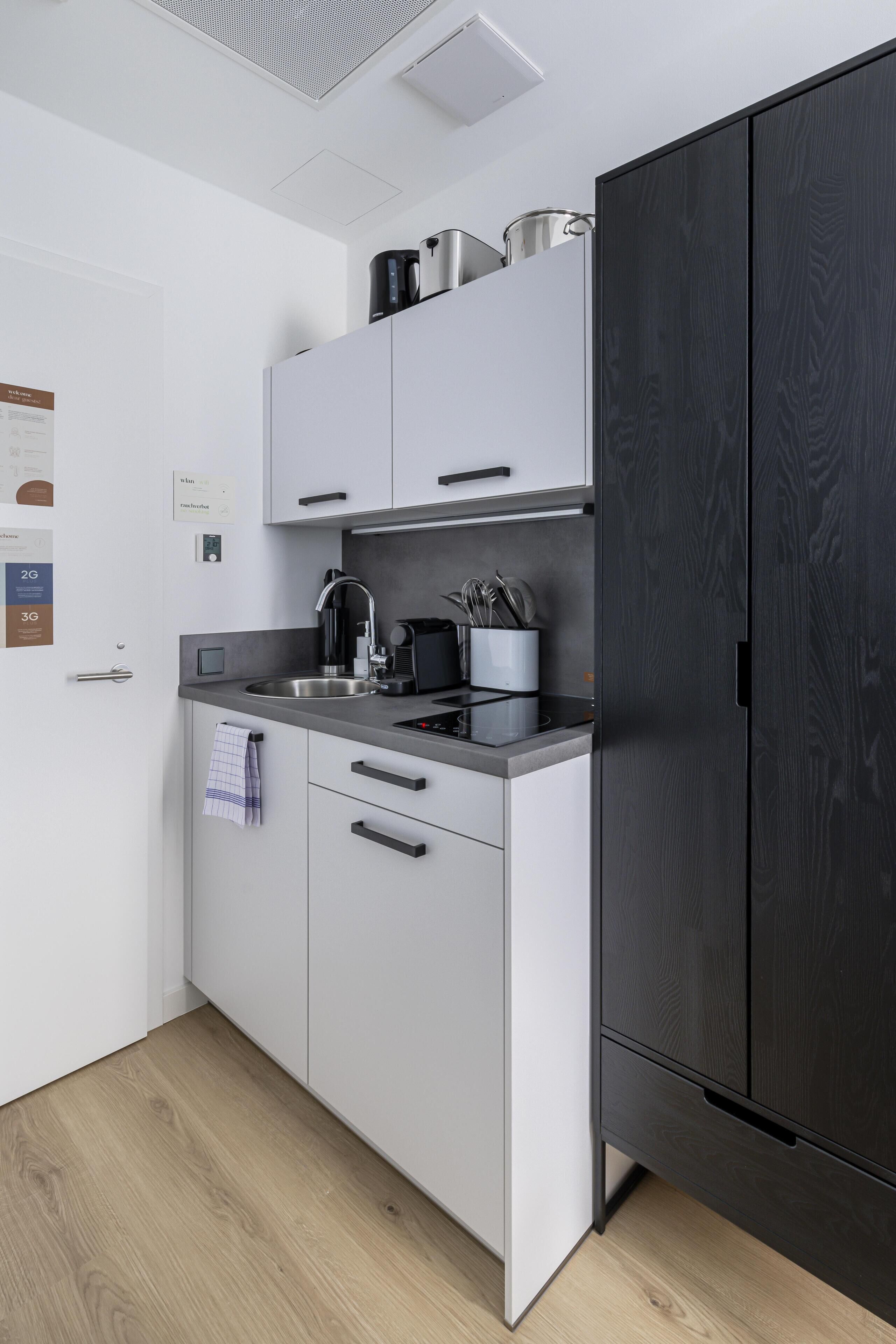 Una cocina moderna con armarios blancos, un refrigerador de madera oscura y un lavamanos de acero inoxidable.