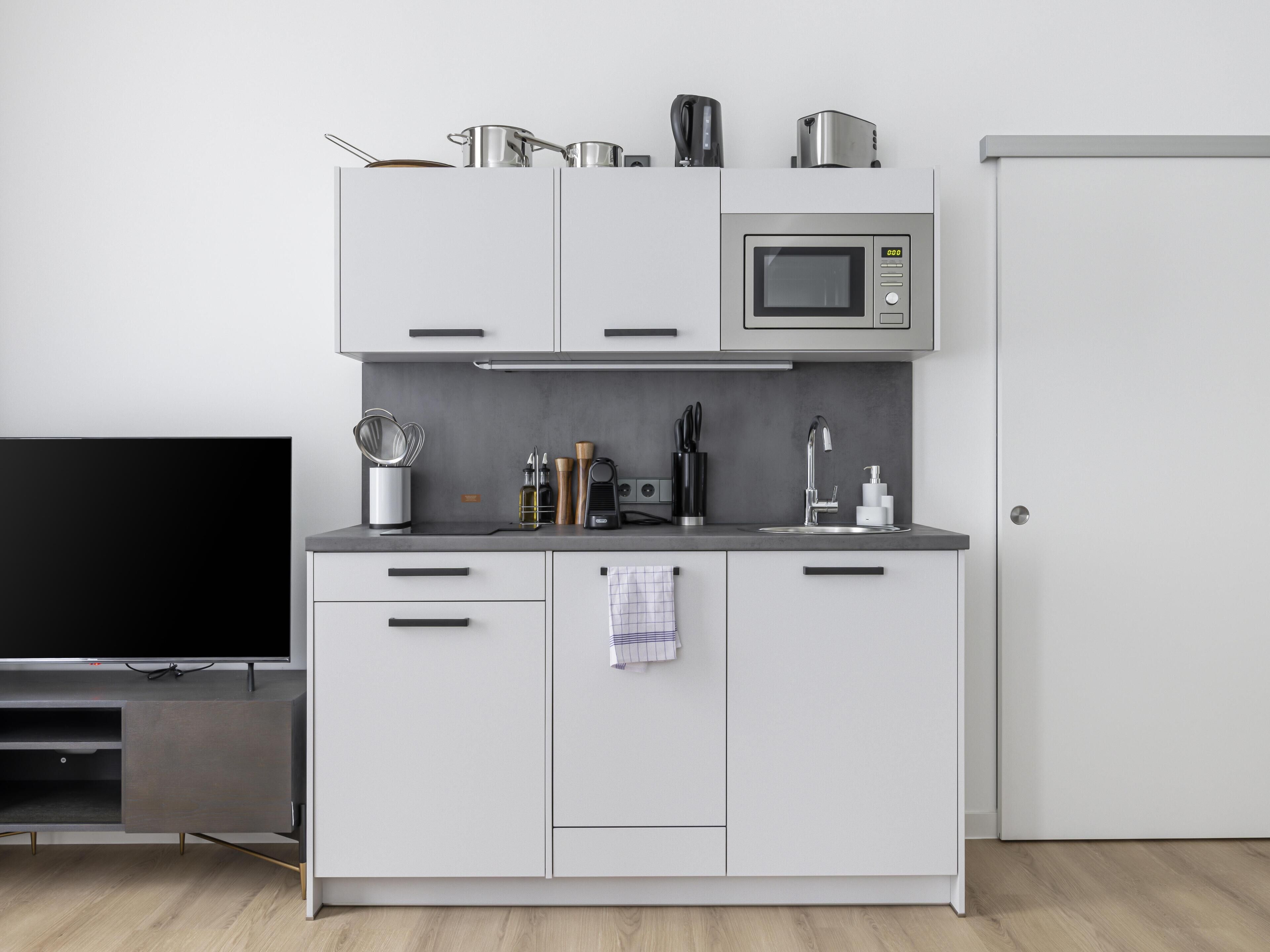 Una kitchenette compacta con microondas, estufa y pileta.